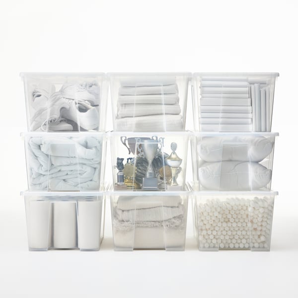 A storage area with transparent SAMLA boxes neatly stacked in rows. In the middle, a box with old sport trophies.