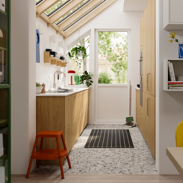 A parallel kitchen with SINARP fronts in oak veneer has high cabinets on one side and base cabinets on the other.