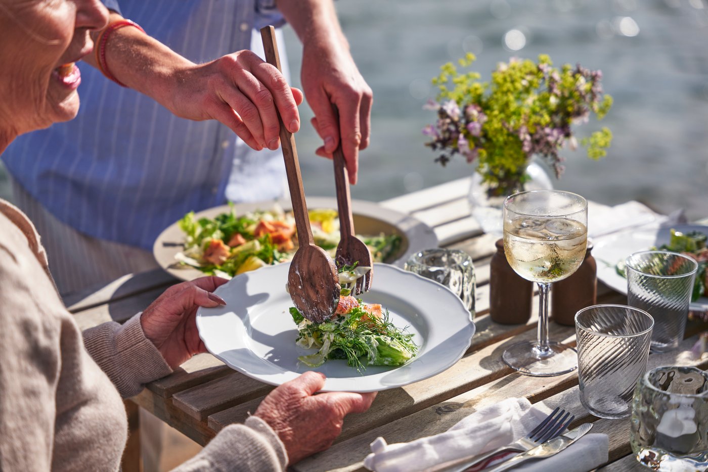 A person placing a salad in a white plate 