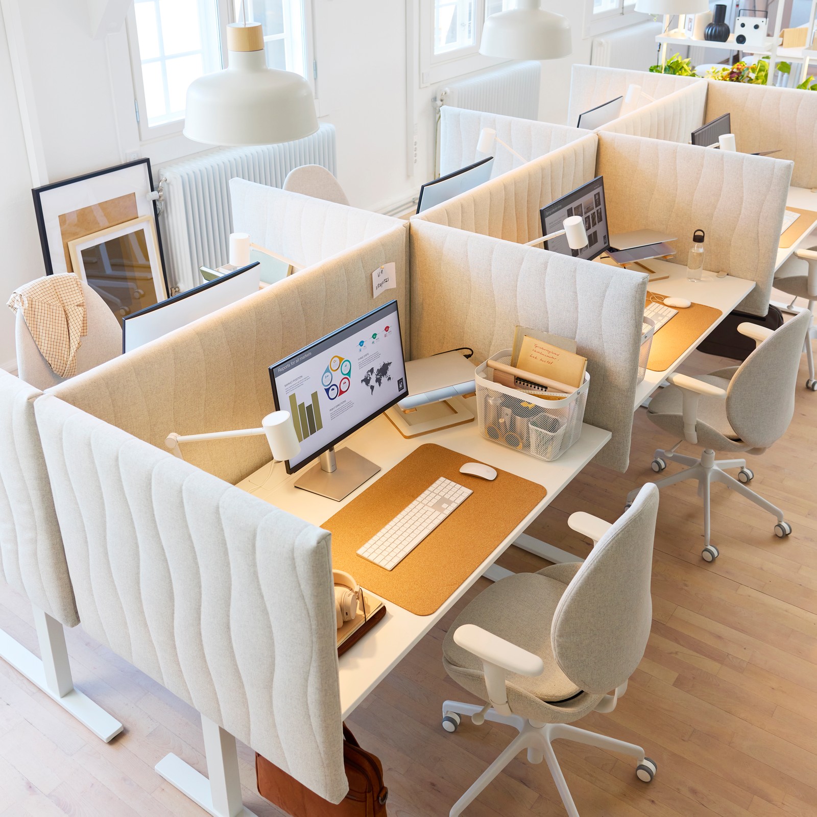 An open office space with electric white MITTZON sit/stand desks and white MITTZON desk chairs.