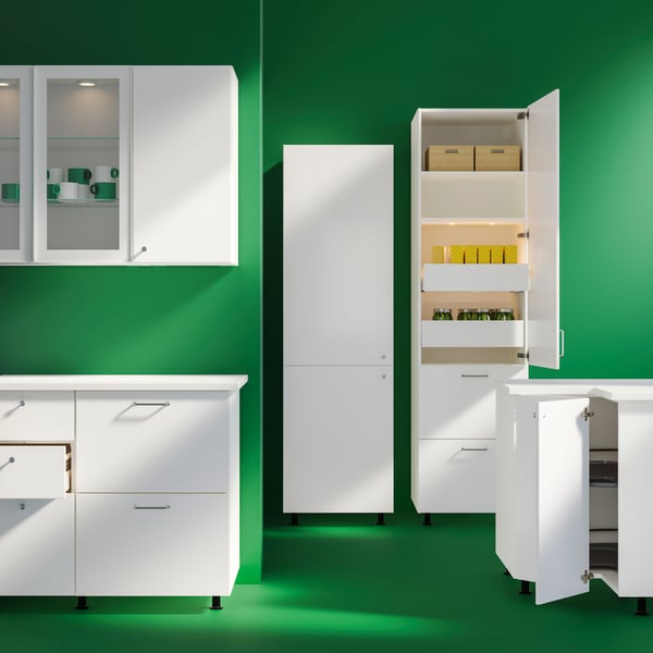 Kitchen cabinets of different sizes and models, some open and some closed, are placed against a dark green background.