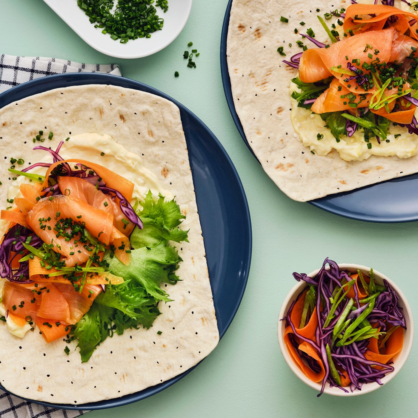 GRÄDDAT soft thin flatbread with SJÖRAPPORT cold-smoked salmon, lettuce, and purple cabbage, served on a table with extra garnish.