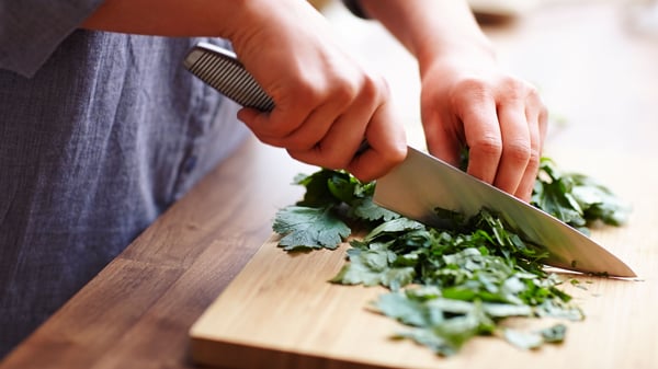 a person chopping herbs with a IKEA 365+ Chef's knife