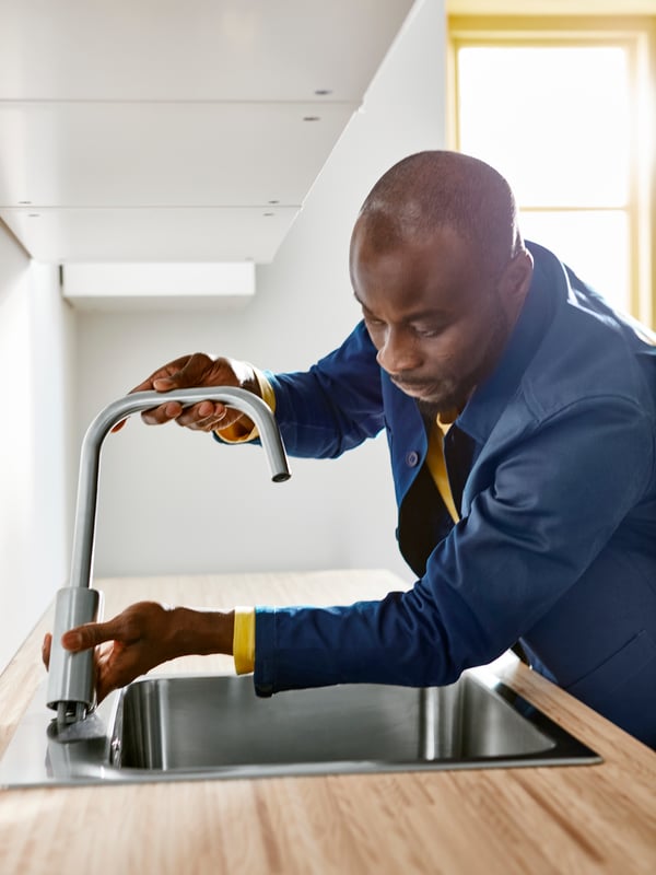 A professional IKEA installer is installing a tap on an IKEA kitchen sink.