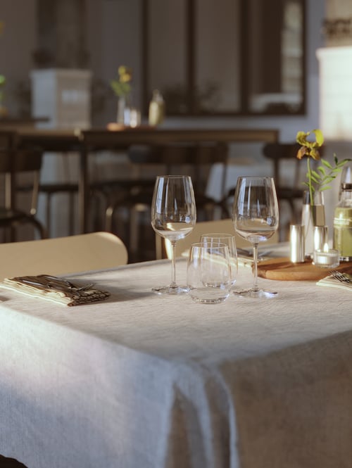Dining room featuring two wine glasses next to two water glasses next to a chopping board on a dining table. 