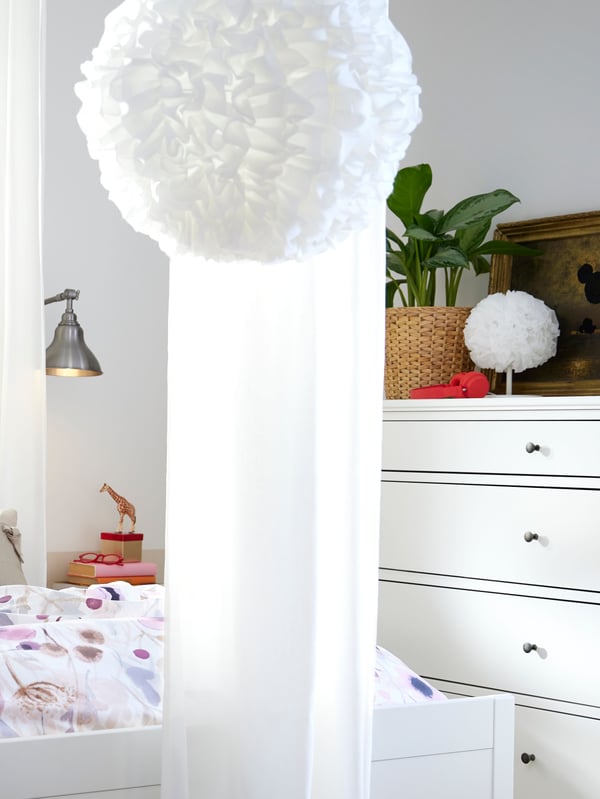 A white VINDKAST table lamp stands on a white IDANÄS chest of 4 drawers by the wall behind a white VINDKAST pendant lamp.