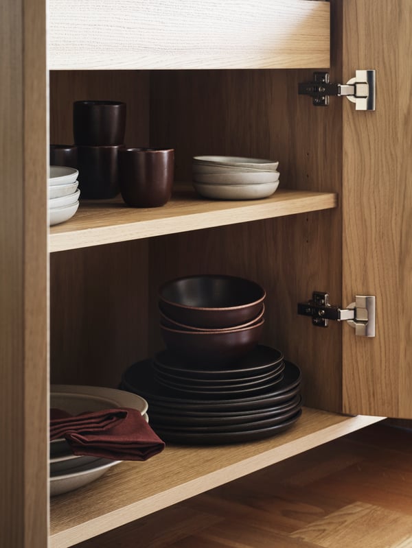 The inside of an IKEA STOCKHOLM 2025 sideboard with IKEA STOCKHOLM 2025 mug