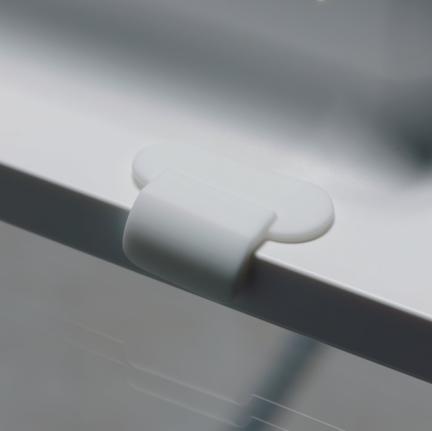 An extreme close-up of a magnetic hook on the back of white SYMFONISK picture frame with WiFi speaker.