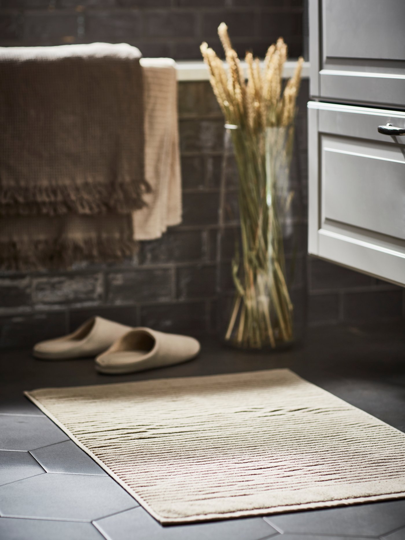 En beige badrumsmatta och ett par tofflor i ett badrum.