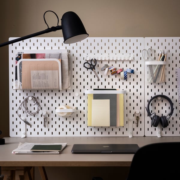 Ein weißes SKÅDIS Board, das an einer Wand hängt.