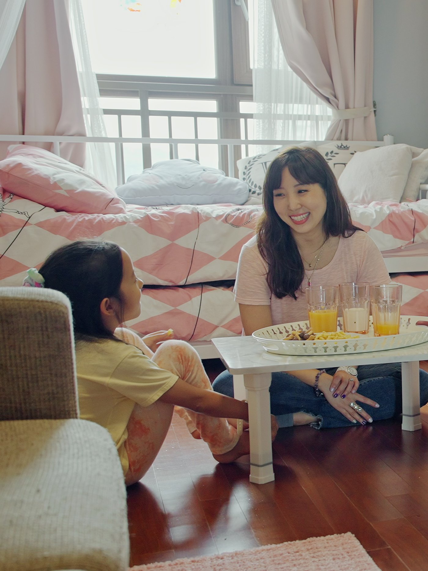 Une mère et son enfant mangent une collation, assises par terre autour d’une table basse dans la chambre à coucher.
