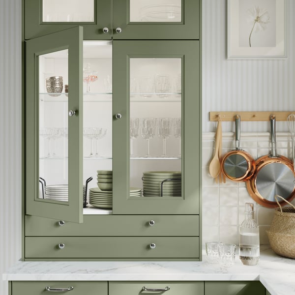 A grey-green AXSTAD glass door open to show green dinnerware