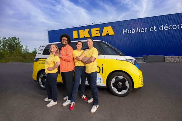 Trois experts IKEA et Zach posant devant le van jaune IKEA + Moi, lui-même devant un magasin IKEA.