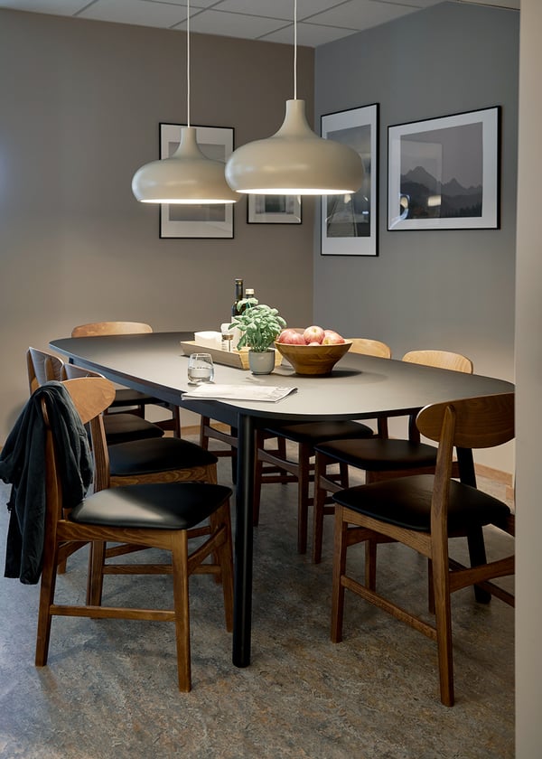 Mötesrum med svart dukat bord omgivet av stolar i valnöt.
