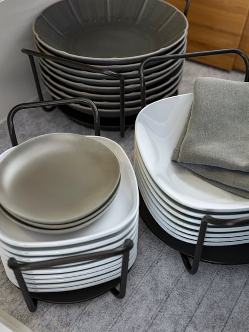 Close-up of three grey plate holders, each containing stacks of plates of different shapes and sizes.