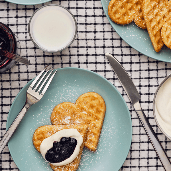 une assiette de gaufres au miel, confiture et crème fouettée avec une fourchette et un couteau
