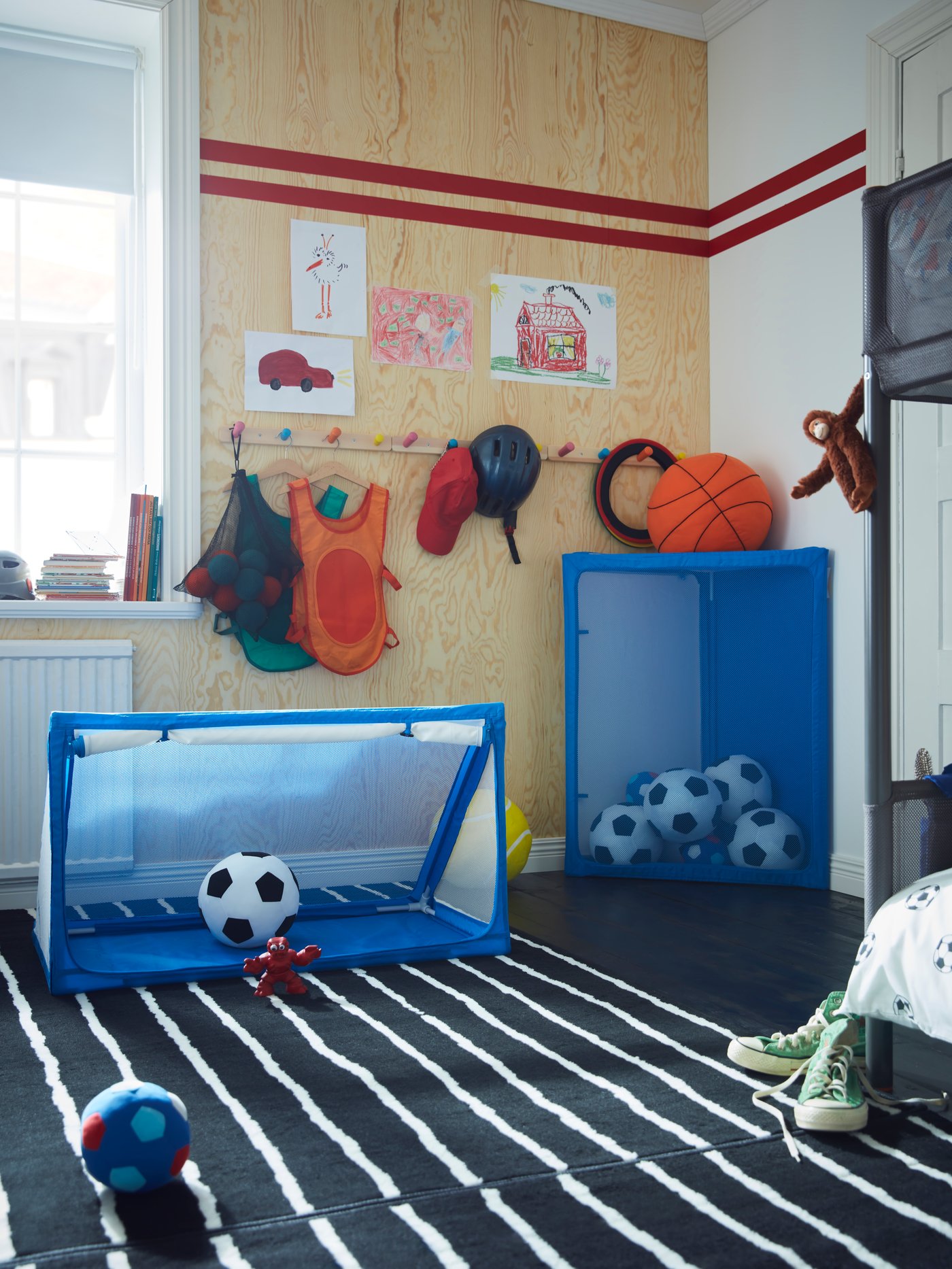 Dos porterías con almacenaje para balones SPORTSLIG en un dormitorio. Una se está usando para jugar, en la otra hay balones guardados.