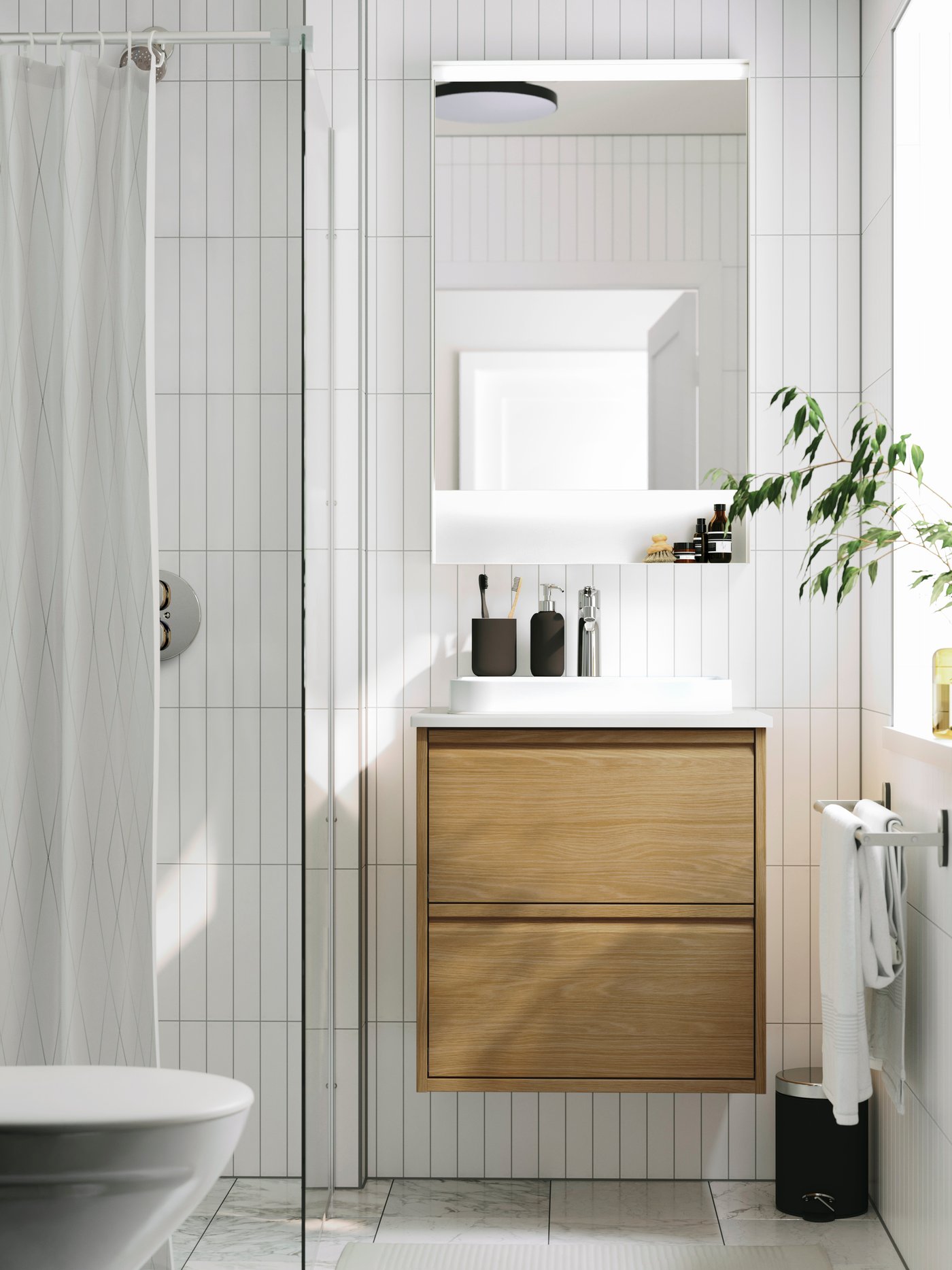 Bright, modern bathroom with a wood vanity, large mirror and white tile walls.ap