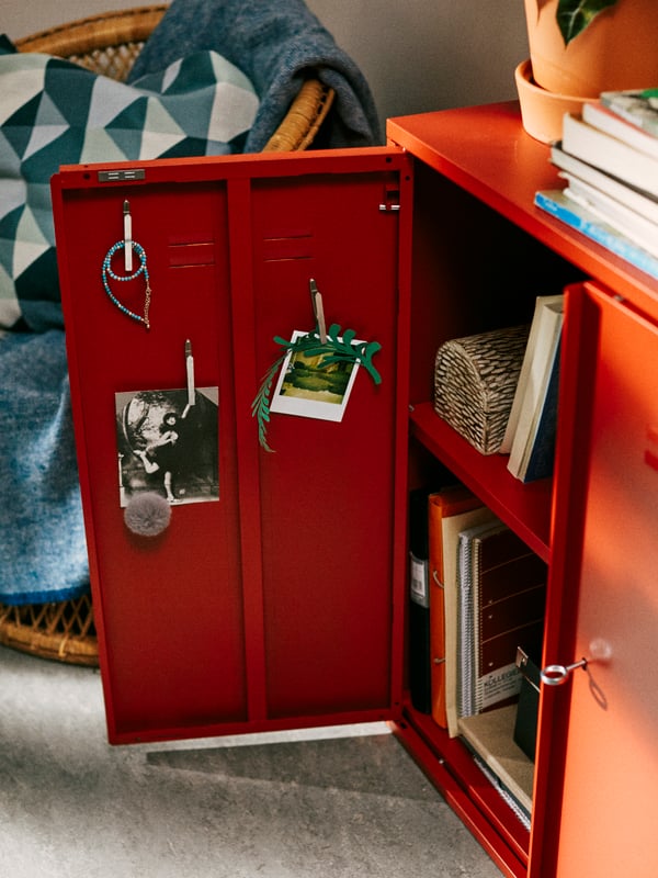 A red IVAR cabinet stands in a student’s bedroom, with one door open showing film photos displayed inside the door.