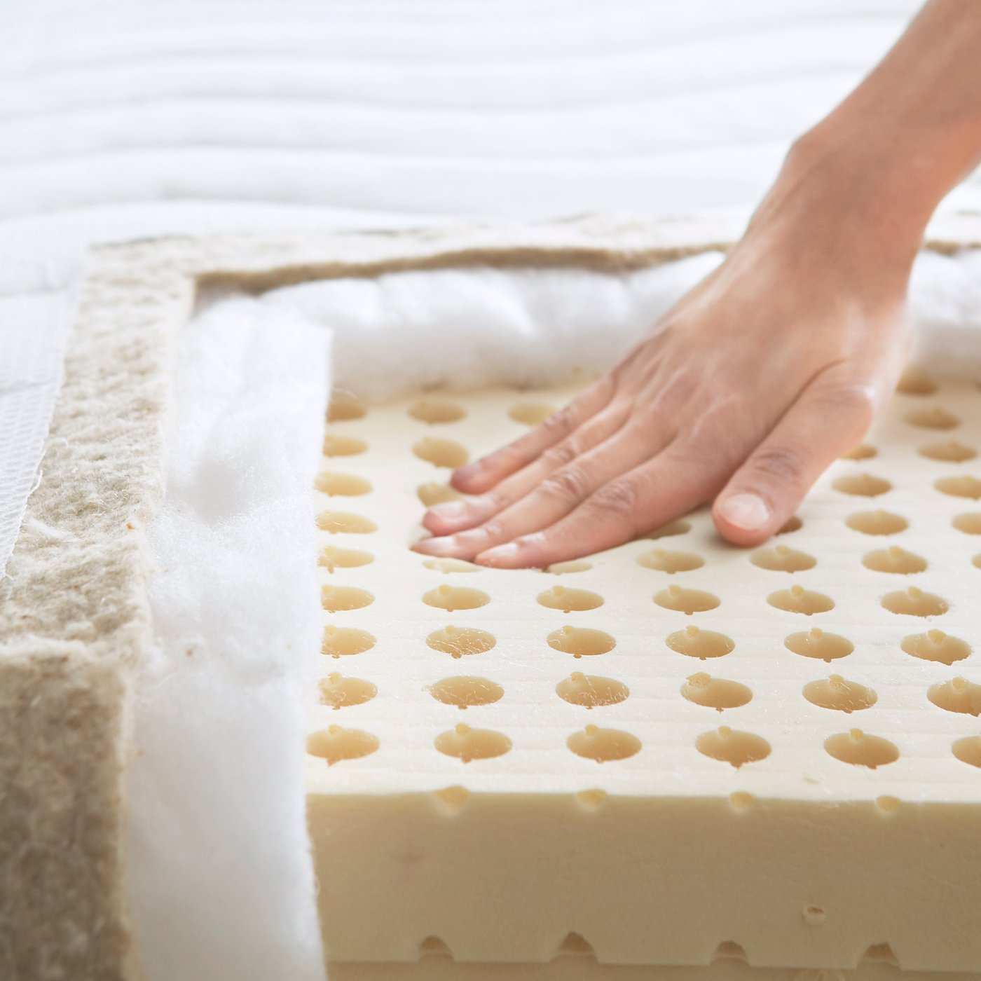 Eine Hand prüft eine aufgeschnittene Matratze.