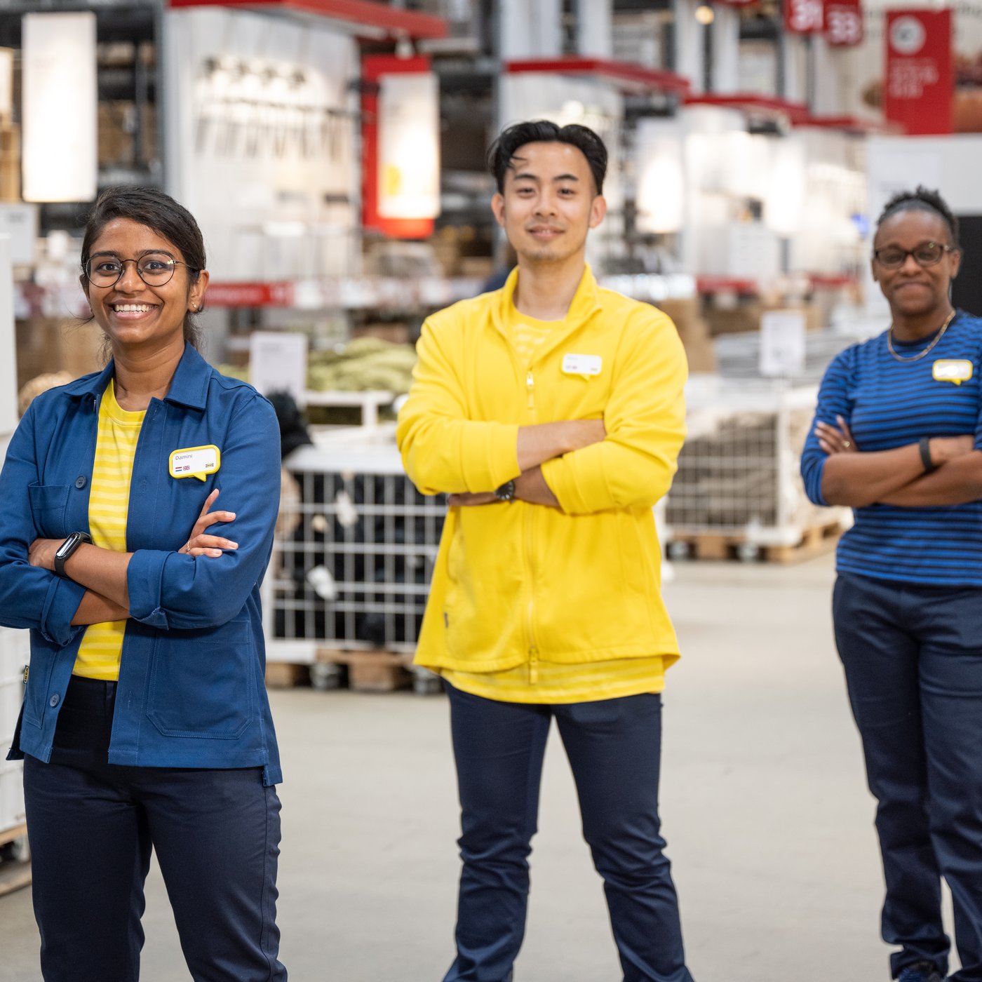 IKEA co-workers looking in the camera and smiling, inside an IKEA store warehouse