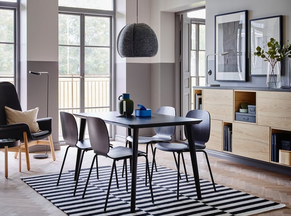 Mesa de comedor de la serie LISABO de color negro con cuatro sillas en el centro de un comedor