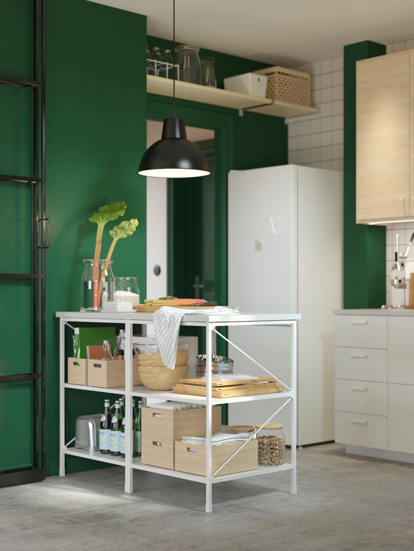 Man sieht eine offene Kücheninsel in einer Küche mit grüner Wand und in der Ecke steht ein VINDÅS
Kühl-/Gefrierschrank