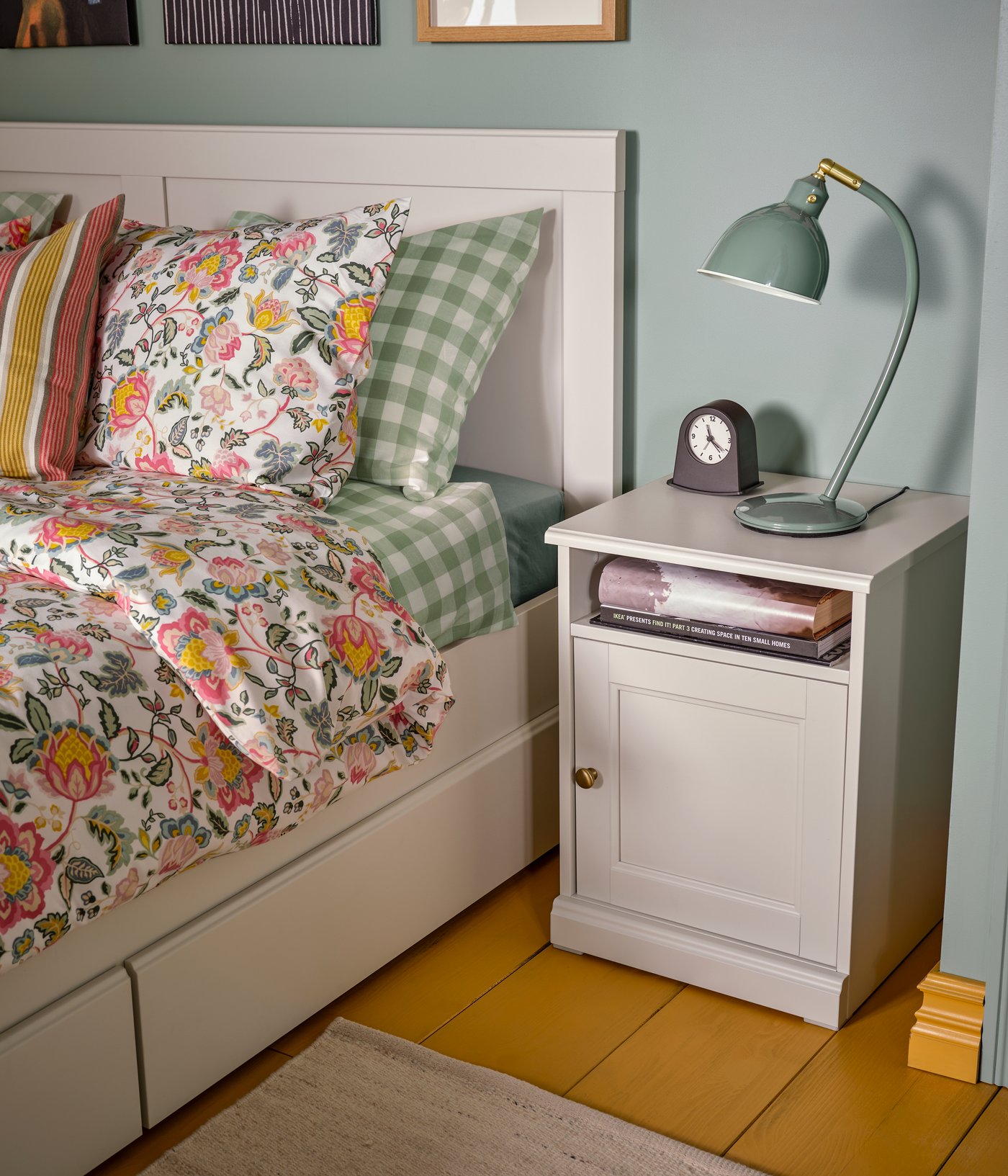 A bedroom with a FÅGELFJÄLLET bedside table and double bed dressed in multicolour/floral pattern DAGGSALVIA bed linen.