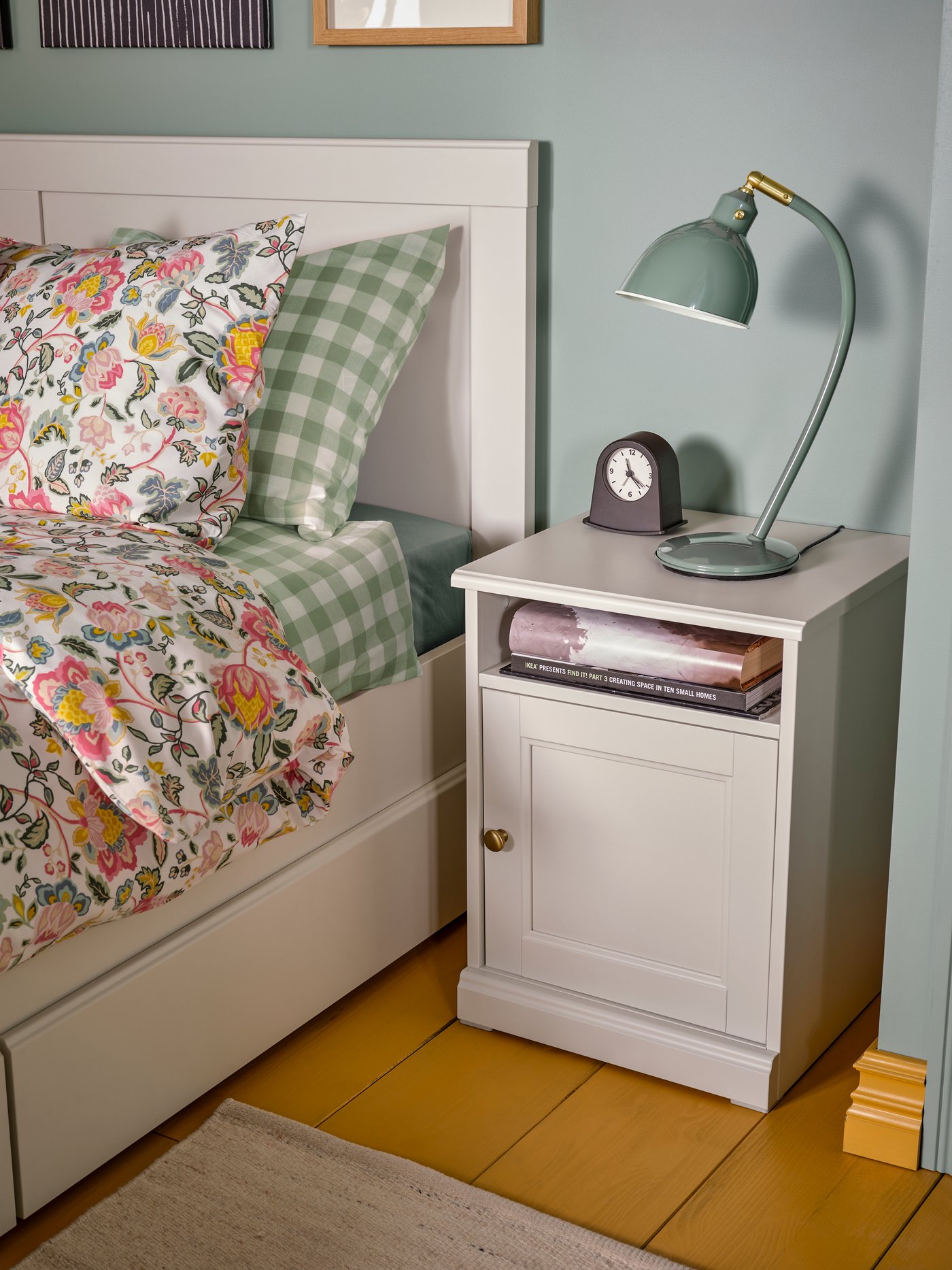 A bedroom with a FÅGELFJÄLLET bedside table and double bed dressed in multicolour/floral pattern DAGGSALVIA bed linen.