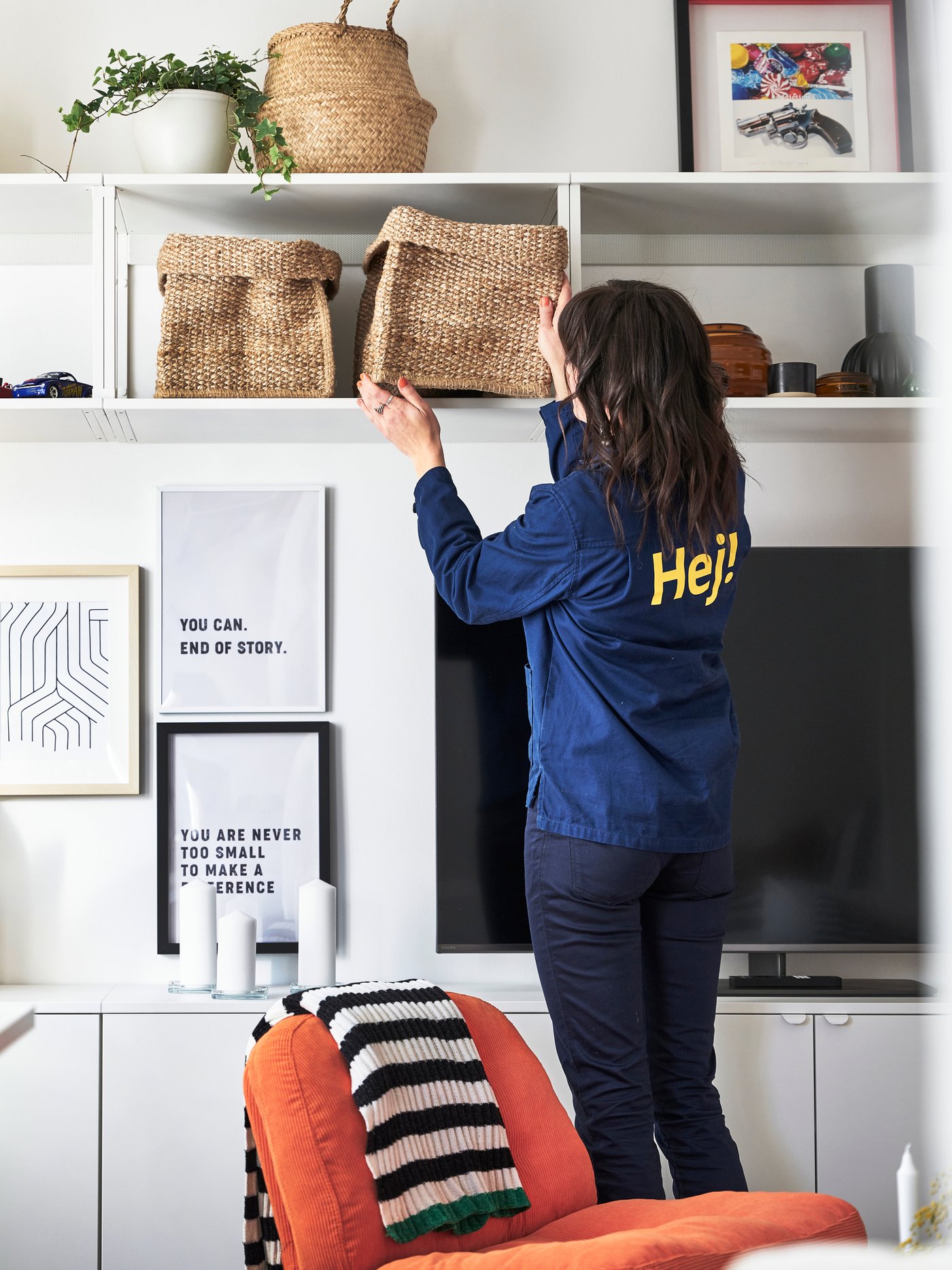 En IKEA inredare plockar ner en flätad förvaringskorg från en vägghylla.