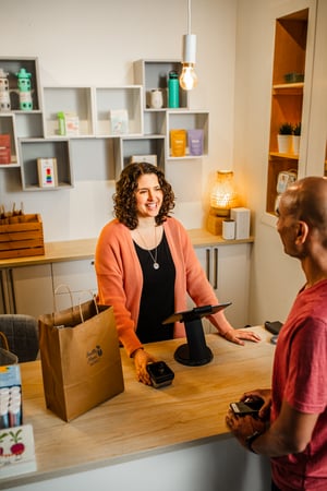 a lady behind a counter checking out a customer