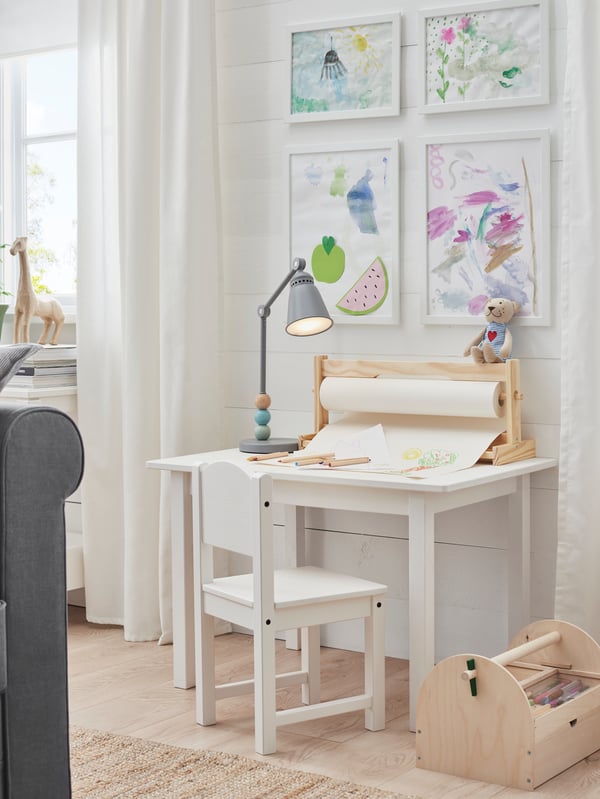 A SUNDVIK children’s chair in front of a SUNDVIK children’s table that has a MÅLA paper roll on top.