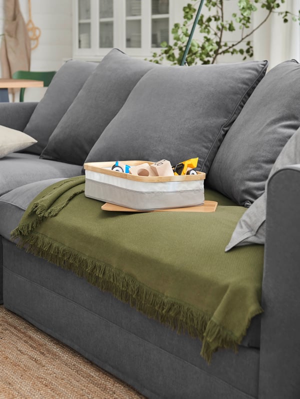 Sofá gris GRÖNLID con una manta verde ODDRUN.