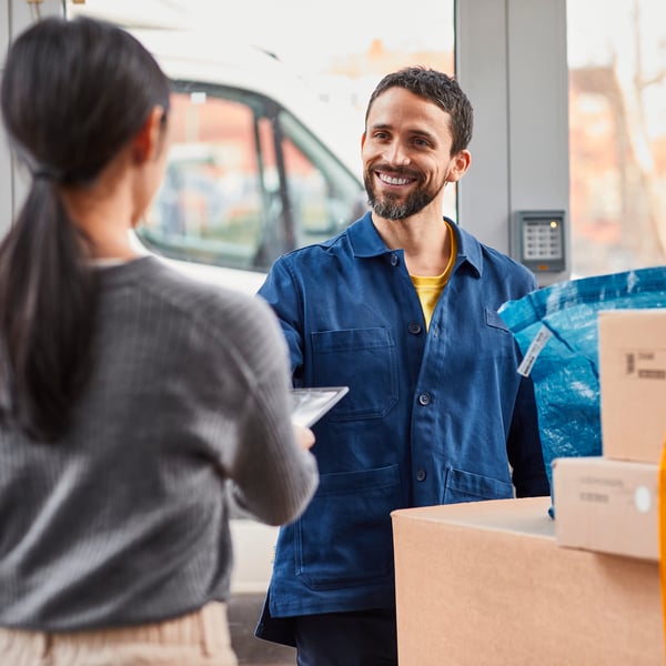 A delivery employee handing over IKEA packages to a customer.