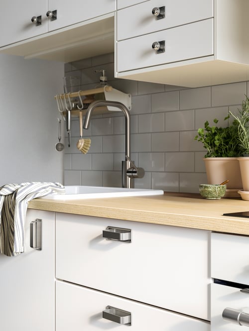 Kitchen with a base cabinet with 4 fronts, 2 low and 3 middle drawers and sleek retro handles, a wall shelf and a mixer tap.