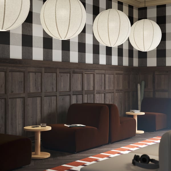 Two dark brown STOCKHOLM seats, paired with pine side tables, with GULLSUDARE pendant lamps hanging from the ceiling.