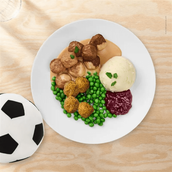 Gerecht met 4 plantaardige balletjes, 4 falafelballetjes en 4 Zweedse gehaktballetjes, erwtjes, aardappelpuree, vossenbessenjam en roomsaus.