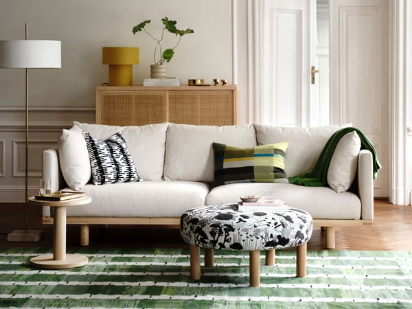 Un lampadaire STOCKHOLM 2025 en textile blanc et laiton plaqué dans le salon