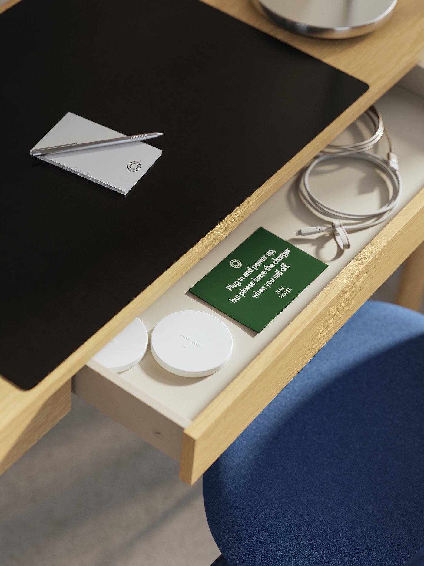 Ett TONSTAD skrivbord i ekfaner med en öppen låda. Inuti finns trådlösa laddare, USB-kablar och en lapp.