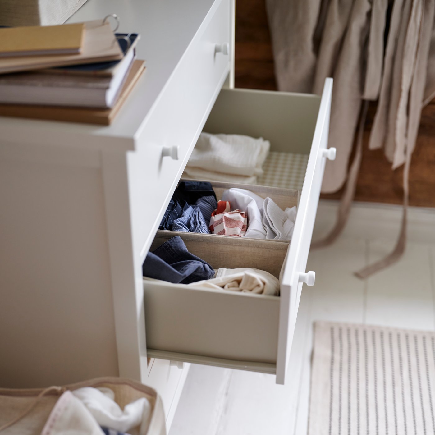 GULLABERG-kommode med 3 skuffer med én skuff trukket ut, som viser pent brettet klær oppbevart inni i et soverom.