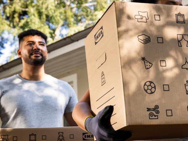Two people are carrying moving boxes.