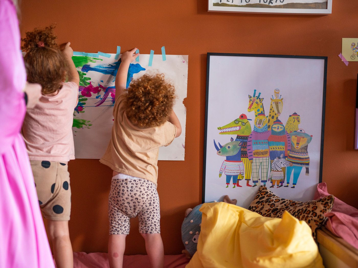 Una mamma e la sua bambina si divertono a dipingere con i colori su un grande foglio di carta appeso alla parete del bagno.