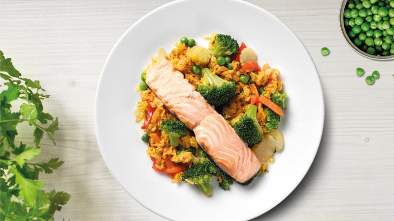 Ein weißer Teller mit einem Lachsfilet und orientalischem Gemüsereis.