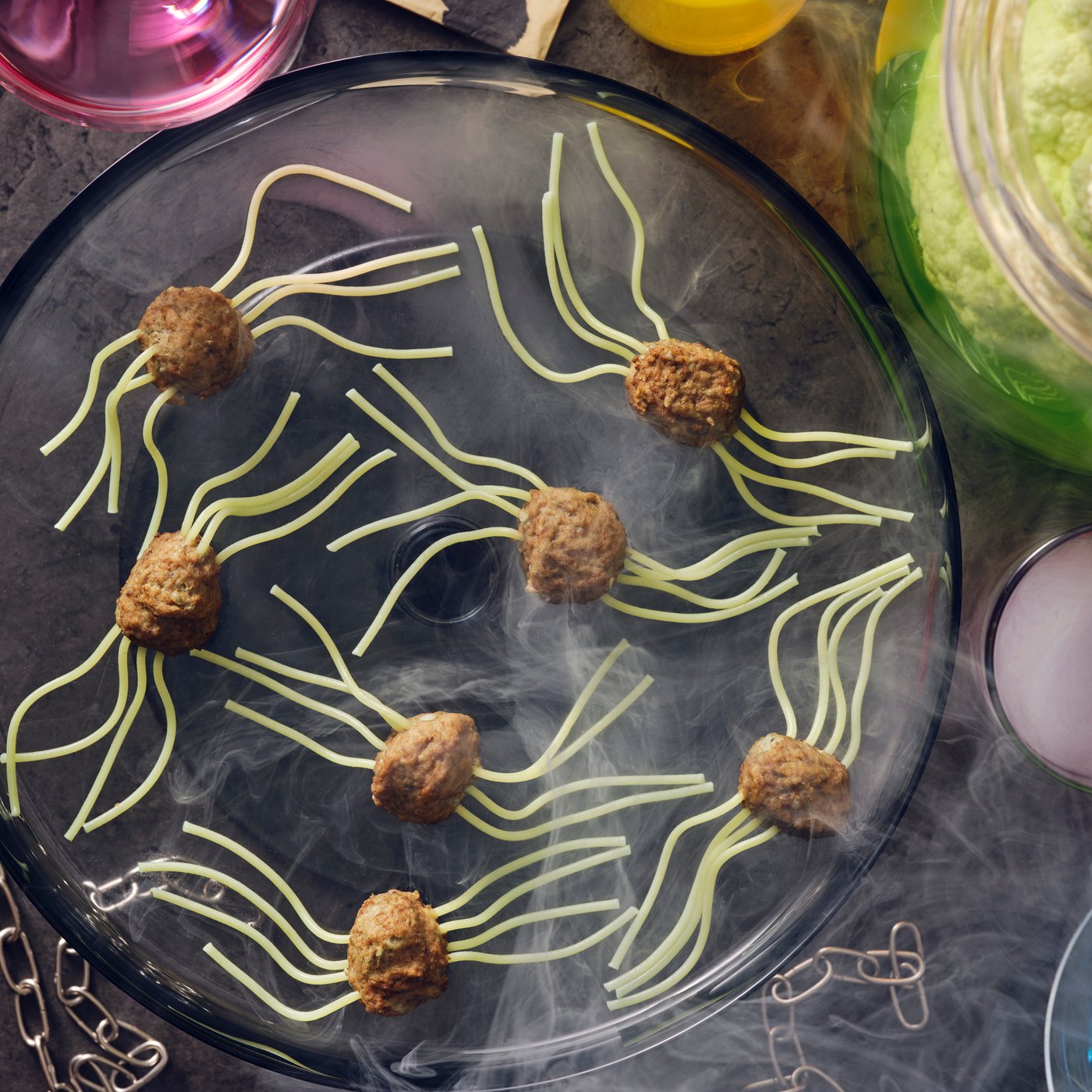 Boulettes-araignées faites de boulettes végétales ou à la viande HUVUDROLL et de spaghettis pour les pattes, posées sur une assiette noire avec de la fumée.