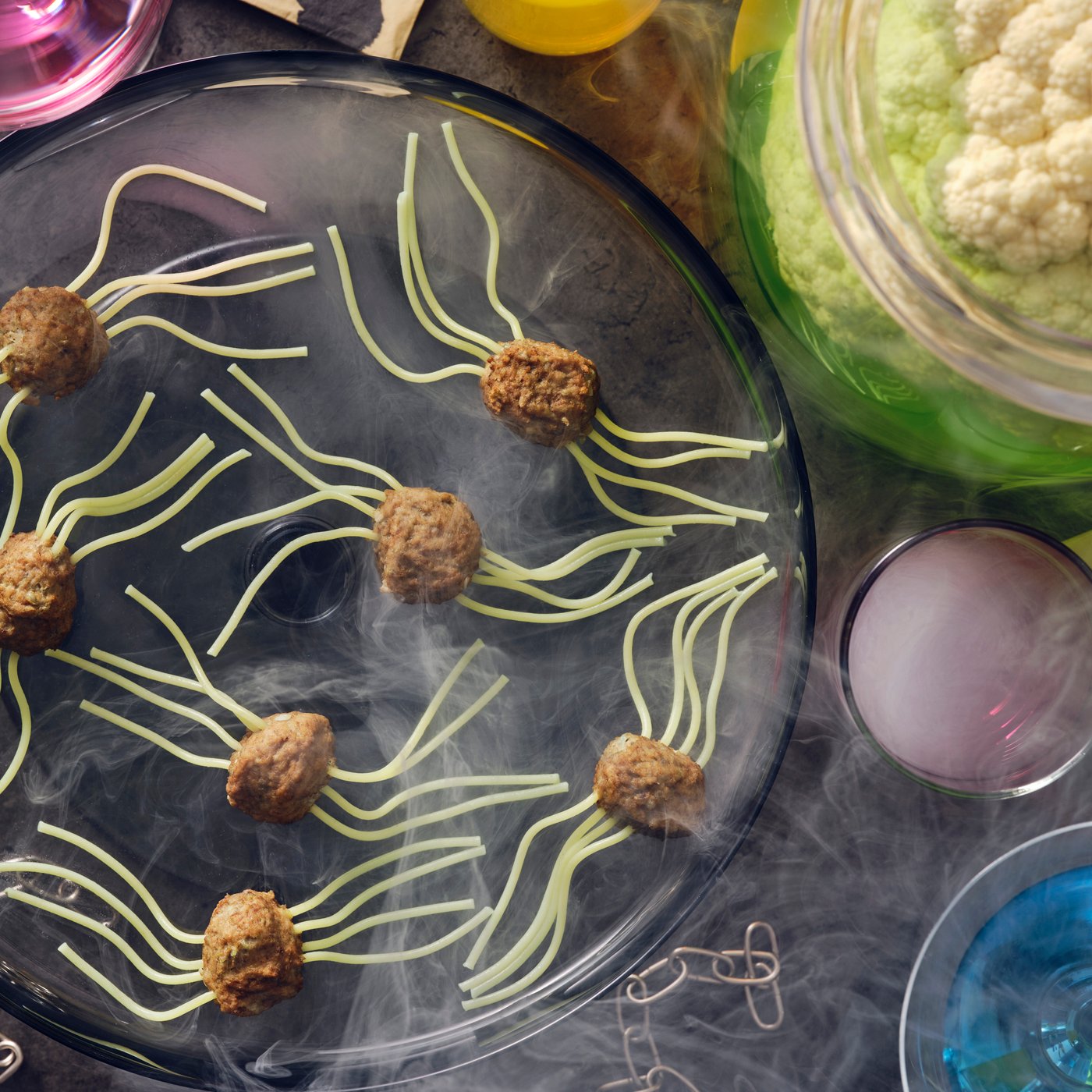 Spider meatballs made with HUVUDROLL plant balls or meatballs and spaghetti for legs laid on a black plate with smoke.