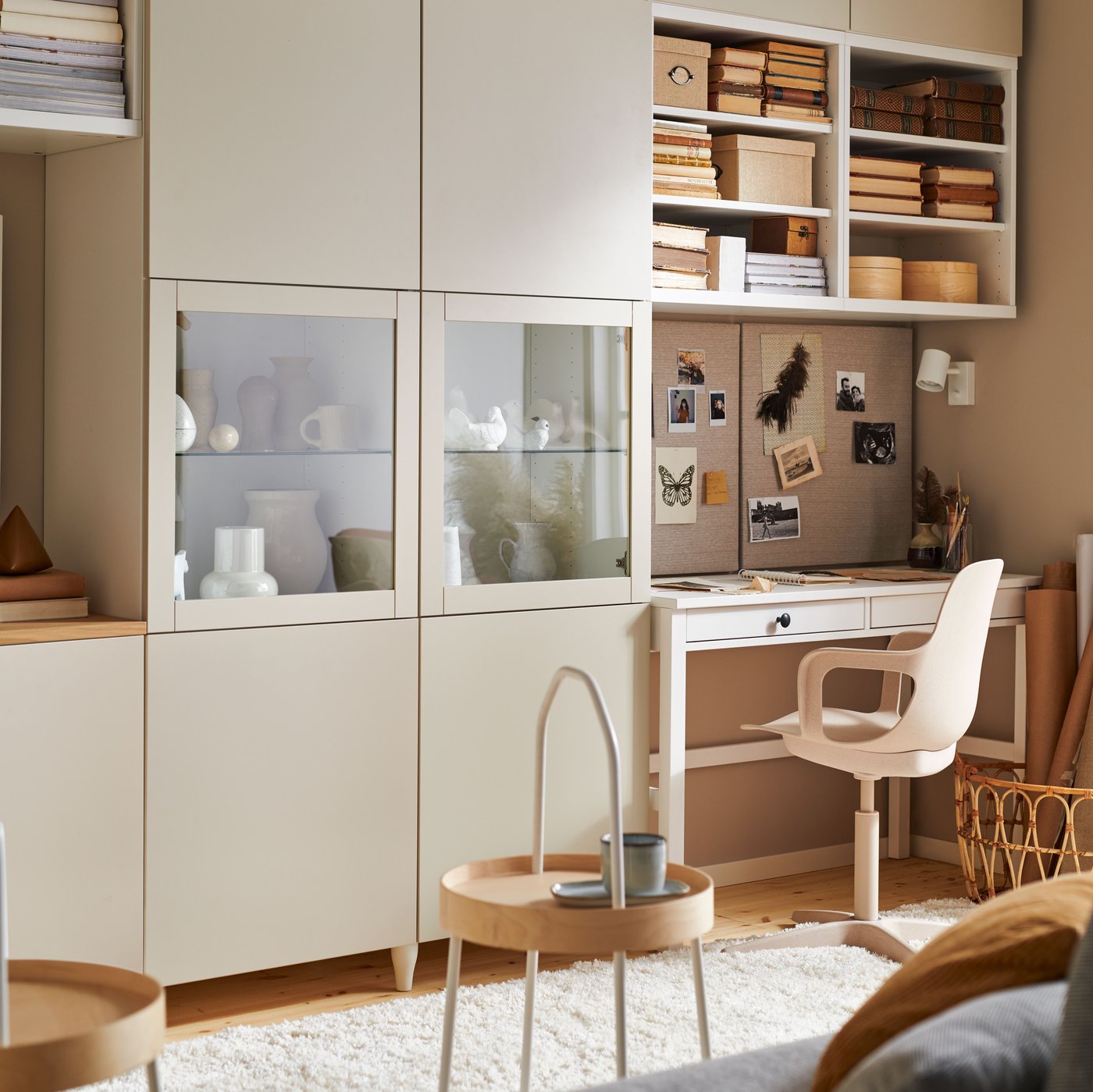 Warmly lit living room featuring the BESTÅ storage combination, white stain HEMNES desk with two drawers and a swivel chair.