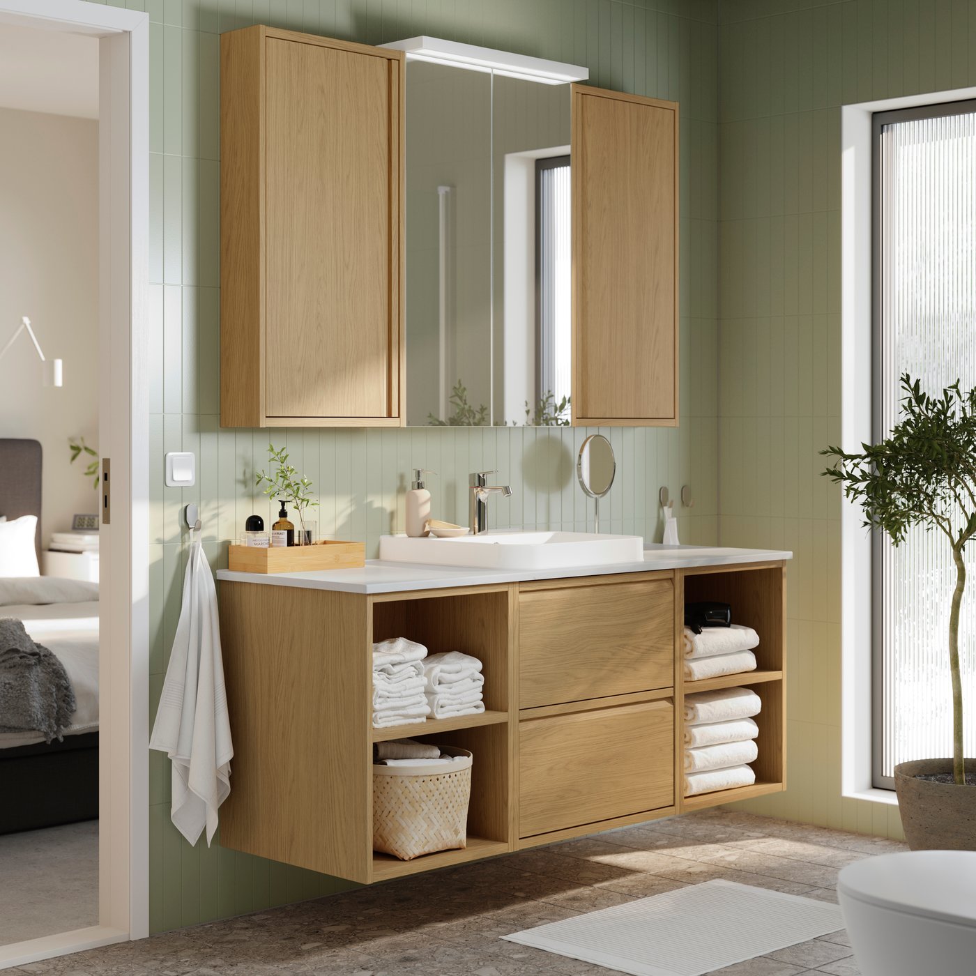 Die ÄNGSJÖN Badezimmerserie, ein Waschbeckenunterschrank in Holzoptik for einer hellgrünen Wand sowie ein Badezimmer Schrank mit Holzoptik und Spiegel.