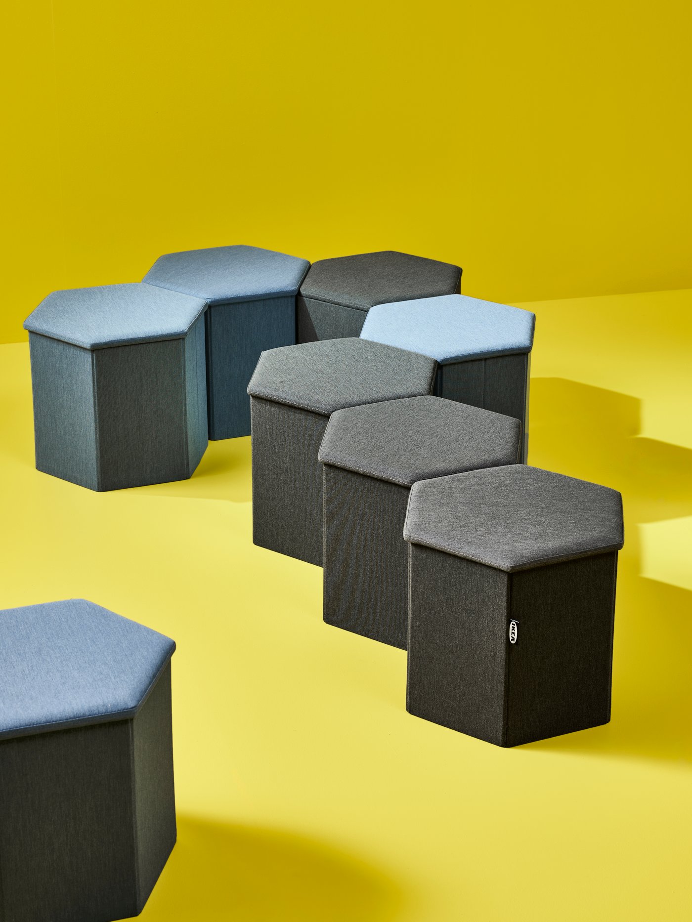 KJUGE pouffes, in Knisa medium blue and in Knisa dark grey, are placed together creating the shape of a question mark.