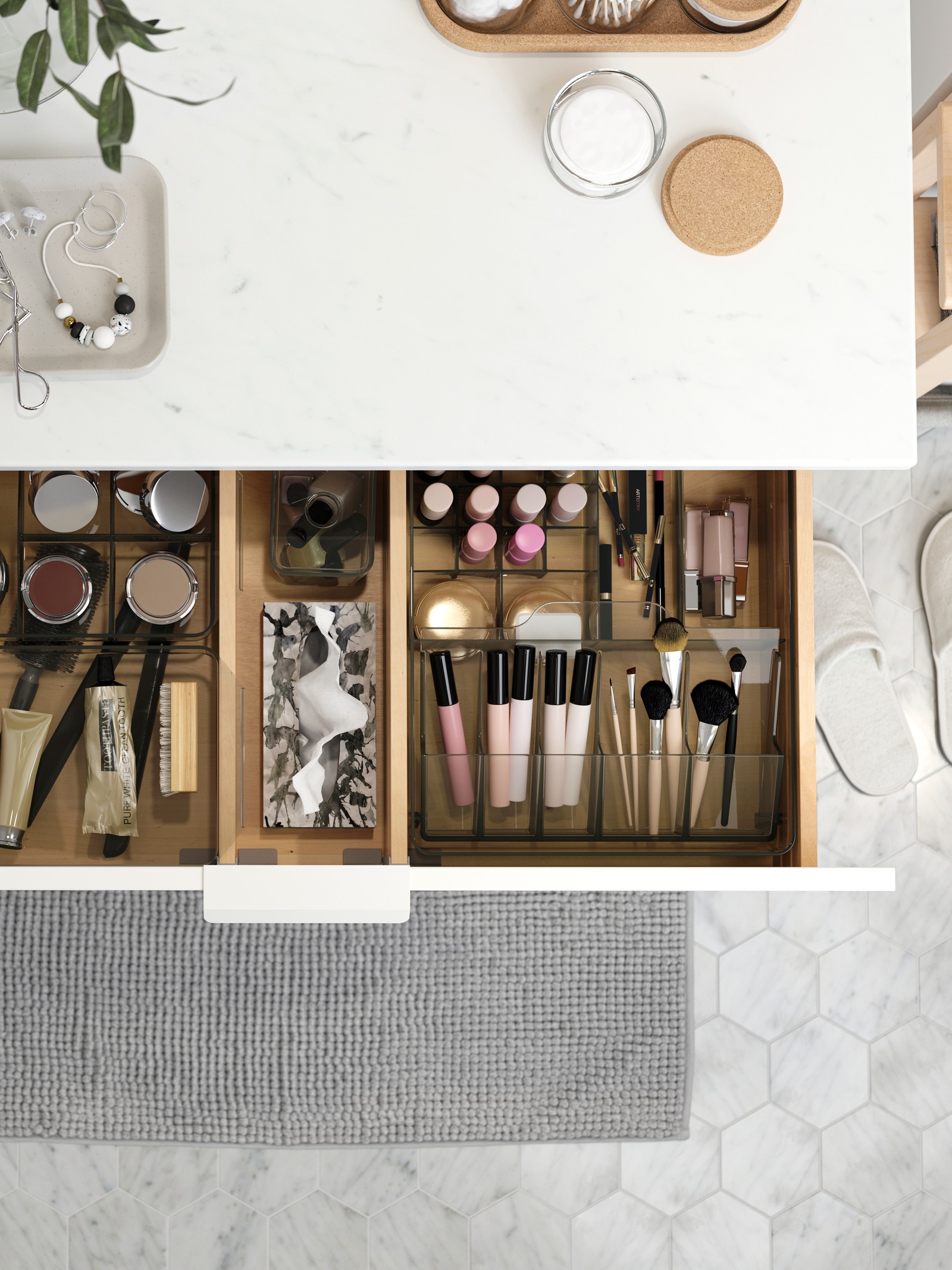 Un mueble de baño con un cajón abieto mostrando artículos de maquillaje ordenados en cajas y separadores.
