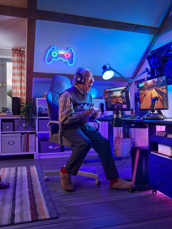 Older man sits in a computer chair havinmg lots of fun and plays video game. 